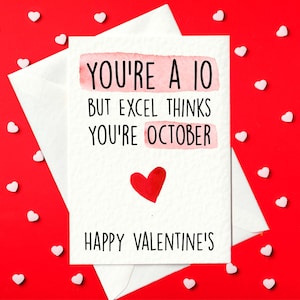 Könnte beinhalten: Eine Valentinstagskarte mit dem Text "YOU'RE A 10 BUT EXCEL THINKS YOU'RE OCTOBER" in schwarzer Schrift, einem roten Herzen und den Worten "HAPPY VALENTINE'S" auf einer weißen Karte. Die Karte befindet sich in einem weißen Umschlag, vor einem roten Hintergrund mit kleinen weißen herzförmigen Dekorationen.