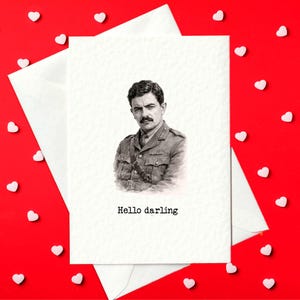 May include: Greeting card with a black and white portrait of a man in a military uniform, with the text "Hello darling" below the portrait. The card is inside a white envelope, set against a red background scattered with white heart-shaped decorations.