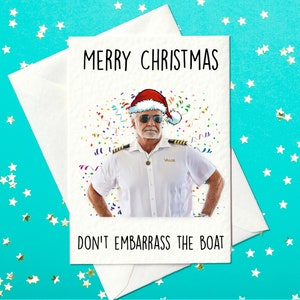 May include: A white greeting card with the text "MERRY CHRISTMAS" and "DON'T EMBARRASS THE BOAT". The card features a man wearing a Santa hat and a white uniform. Confetti is scattered around the man. The card is inside a white envelope.