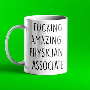 Könnte beinhalten: Eine weiße Keramik-Kaffeetasse mit schwarzem Text, der "FUCKING AMAZING PHYSICIAN ASSOCIATE" lautet