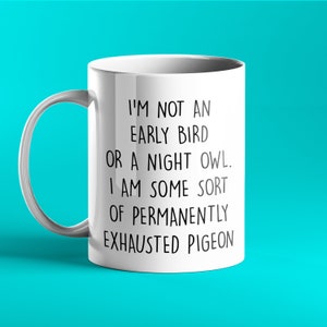 Pu&ograve; includere: Una tazza in ceramica bianca con testo nero che recita: "Non sono un mattiniero n&eacute; un gufo. Sono una specie di piccione permanentemente esausto."