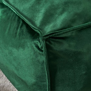 May include: Close-up of a deep green velvet fabric with a seam running along the edge.