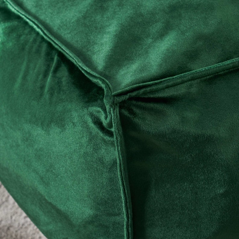May include: Close-up of a deep green velvet fabric with a seam running along the edge.