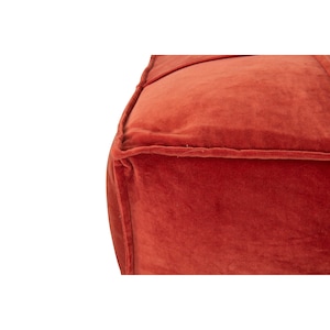 May include: A large, square, red velvet ottoman with a tufted top and a stitched seam around the edges.