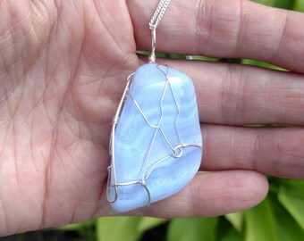 May include: A blue agate pendant wrapped in silver wire, hanging from a silver chain.
