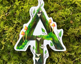 May include: A die-cut sticker shaped like the letter A, featuring a dark brown tree bark texture covered in vibrant green moss. The design includes small orange mushrooms, delicate green leaves, and white shelf fungi, with the text Wandering Arts & Crafts.