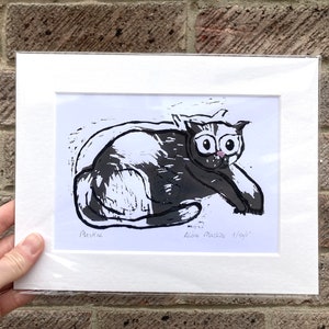 May include: Black and white linocut print of a cat with the text "Periwinkle" and "Alana Marble 1/40" in the bottom corners.