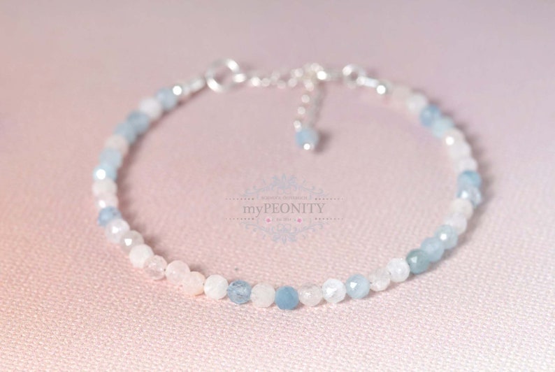 May include: A delicate bracelet made with light blue and white gemstone beads. The bracelet has a silver clasp and extender chain.