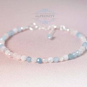 May include: A delicate bracelet made with light blue and white gemstone beads. The bracelet is made with a silver chain and clasp.