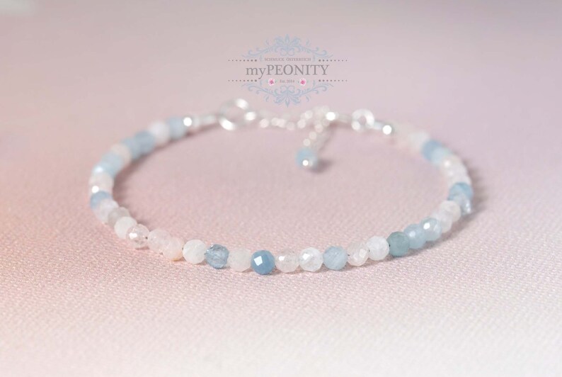 May include: A delicate bracelet made with light blue and white gemstone beads. The bracelet is made with a silver chain and clasp.