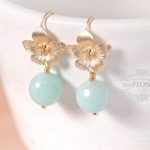 May include: Gold flower dangle earrings with light blue round gemstone drops.