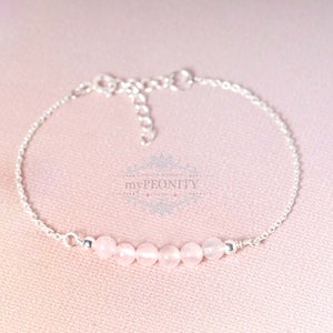 Puede incluir: Un delicado brazalete de cadena de plata con una fila de seis cuentas de piedras preciosas de color rosa p&aacute;lido.