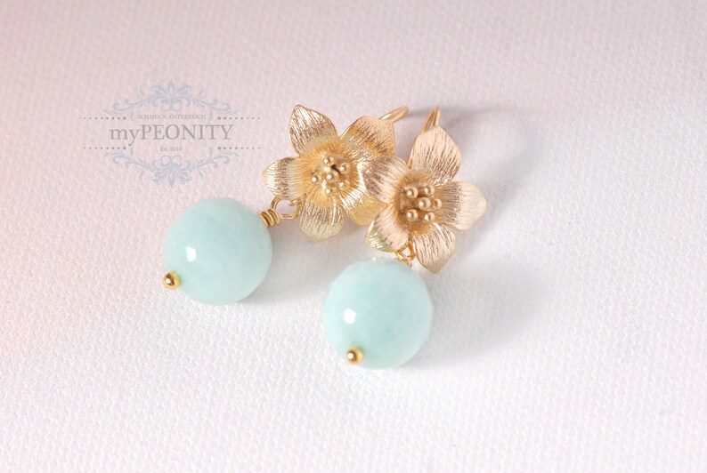 May include: Gold flower earrings with light blue round gemstone drops.