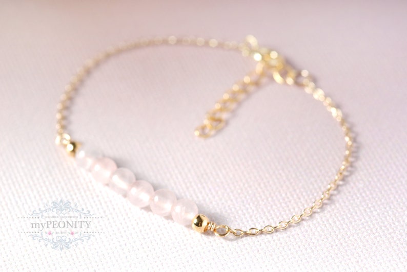 Puede incluir: Un delicado brazalete de cadena dorada con una fila de cuentas de color rosa p&aacute;lido. El brazalete es simple y elegante, perfecto para el uso diario.