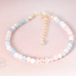 May include: A delicate bracelet made with light blue and pink beads, accented with a gold chain clasp.