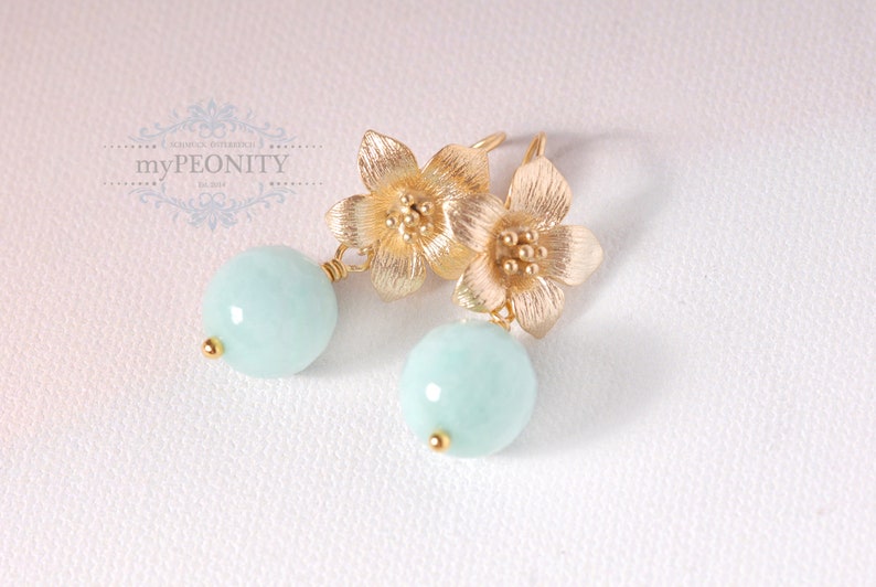 May include: Gold flower earrings with light blue round gemstone drops.