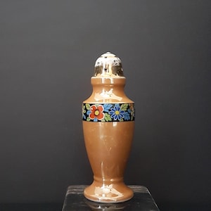 May include: A vintage ceramic salt shaker. It has a tan body and a decorative band of colourful flowers. The top is silver-coloured with small holes for dispensing salt. A classic kitchenware item.
