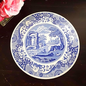 Peut inclure: Une assiette décorative ronde, blanche et bleue, avec une scène de paysage. L'assiette présente un motif bleu et blanc détaillé avec une image centrale de paysage entourée de motifs floraux et de volutes. Une pièce de vaisselle classique.