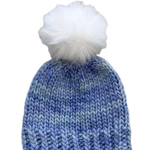 May include: A blue and white knitted beanie with a fluffy white pom pom on top.