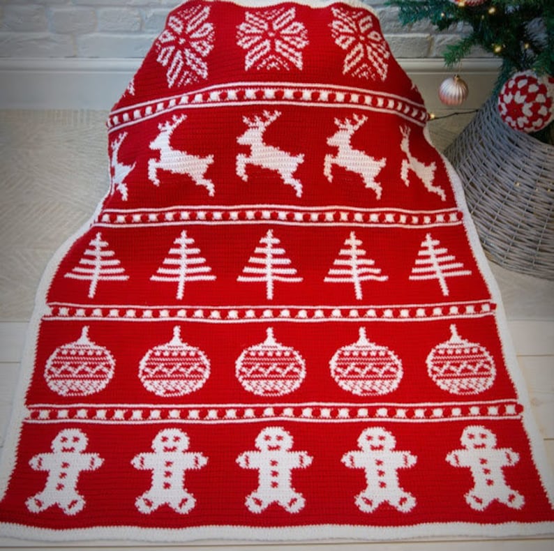 May include: Red and white crocheted blanket with a Christmas theme. The blanket features snowflakes, reindeer, Christmas trees, ornaments, and gingerbread men.