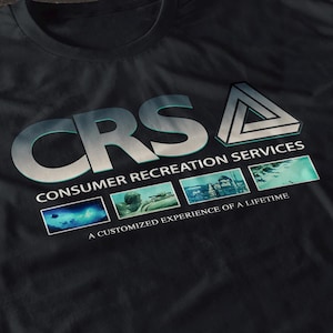 以下が含まれることがあります： グラデーションの青と銀色のフォントで「CRS CONSUMER RECREATION SERVICES」というテキストがプリントされた黒いTシャツ。テキストの下には3つの小さな画像と「A CUSTOMIZED EXPERIENCE OF A LIFETIME」というテキストがあります。右側には三角形のロゴがあります。