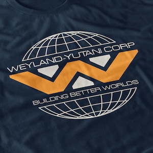 Puede incluir: Camiseta azul marino con el logotipo de Weyland-Yutani Corp. El logotipo incluye una forma de "W" naranja estilizada, texto blanco y un diseño de globo. El texto dice "WEYLAND-YUTANI CORP" y "BUILDING BETTER WORLDS".