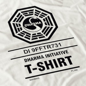 May include: White t-shirt with a black Dharma Initiative logo and text. The shirt displays "DI 9FFTR731", "Dharma Initiative", and "T-SHIRT". The shirt also has the numbers "PL390" and "960VKKS".