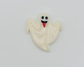 May include: A white ghost figurine with a red tongue sticking out and black eyes. The ghost is in a flying pose with its arms outstretched.