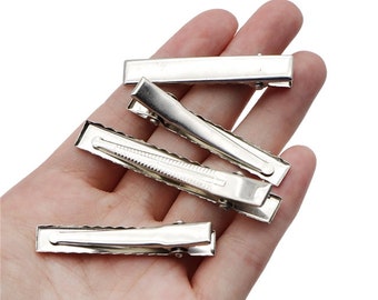 May include: Four silver metal hair clips. The clips are rectangular and have a smooth finish. They are ideal for holding hair in place.