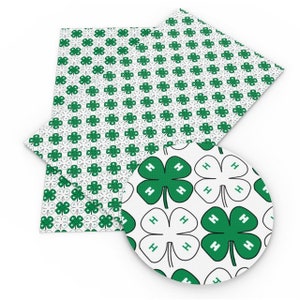 May include: White fabric with a green four-leaf clover pattern. The clover has the letter "H" in each leaf.