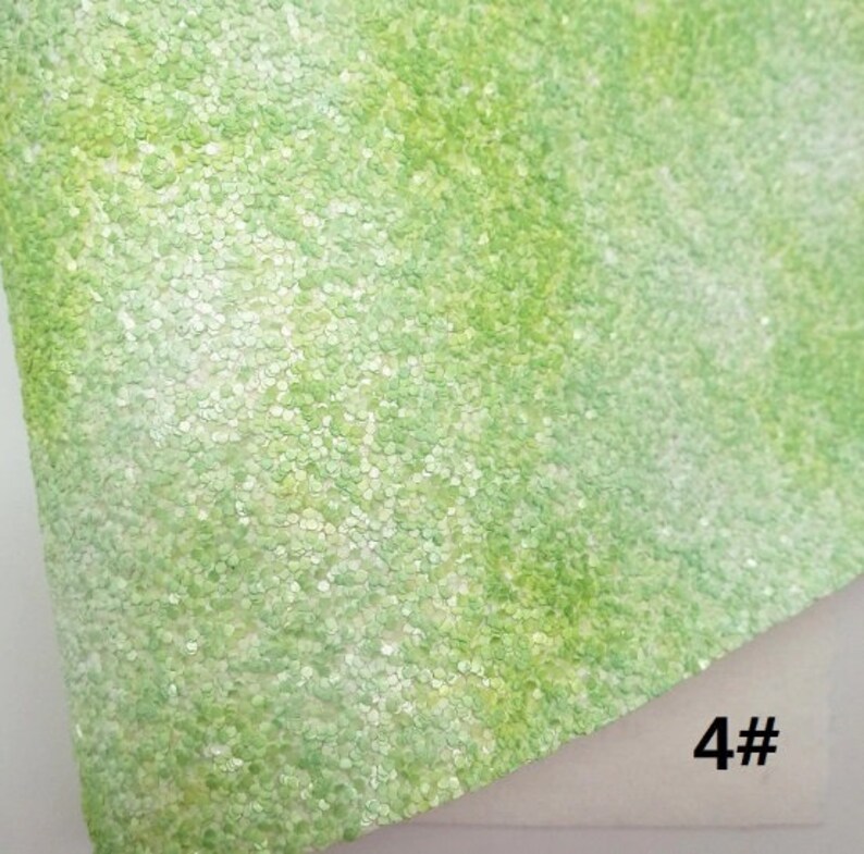 May include: Close-up of a sheet of green glitter fabric. The fabric has a textured surface with small, round, light green sequins. The number "4#" is visible in the bottom right corner.