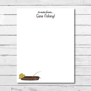 May include: A white notepad with the text "A note from... Gone fishing!" printed at the top. A cartoon illustration of a fishing boat with a hat on top is at the bottom of the notepad.