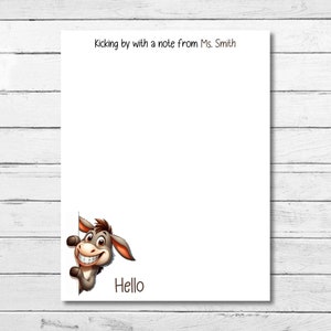 May include: A white note card with the text "Kicking by with a note from Ms. Smith" at the top. A cartoon donkey peeks from the bottom right corner with the word "Hello" below it.