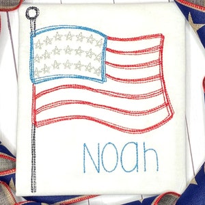 May include: A white t-shirt with an embroidered American flag and the name "Noah" in blue thread.