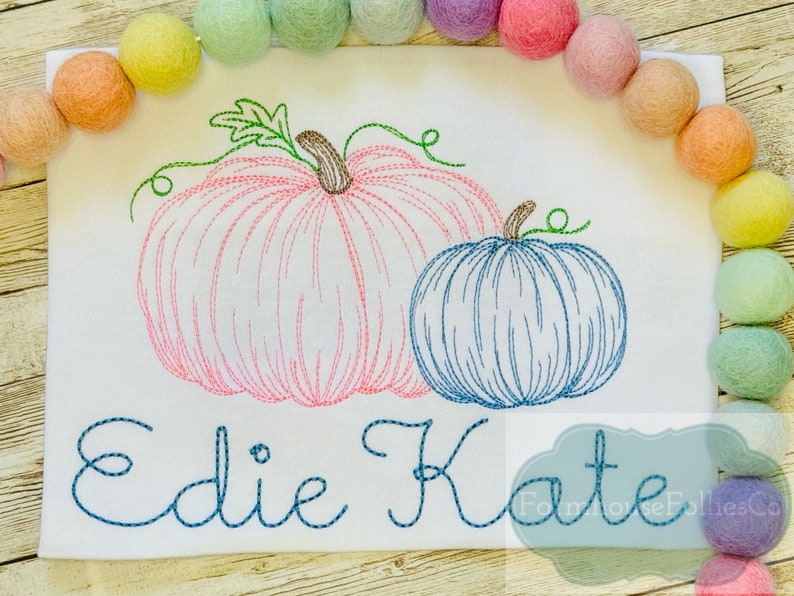 Puede incluir: Dise&ntilde;o bordado de dos calabazas, una rosa y una azul, con los nombres "Edie Kate" cosidos debajo.