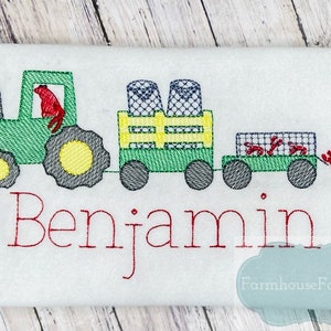 May include: Green tractor pulling a wagon with a red lobster and a name "Benjamin" embroidered on a white fabric.