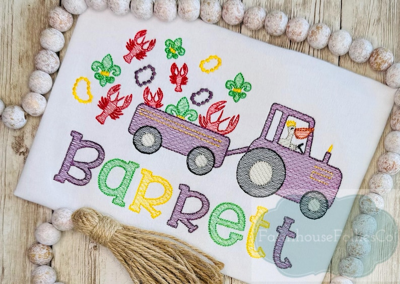 K&ouml;nnte beinhalten: Gestickte Darstellung eines lila Traktors, der einen Wagen voller Krebse zieht, mit einem Pelikan am Steuer. Der Wagen ist mit Mardi Gras-Perlen und Fleur-de-lis verziert. Der Name "Barrett" ist unter dem Traktor in bunten Buchstaben gestickt.