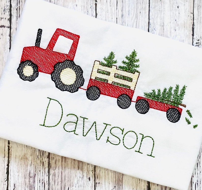 May include: Red toy tractor pulling a wagon with Christmas trees. The wagon is filled with green trees and the tractor has the name Dawson embroidered on the front.
