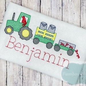 May include: Green tractor with a red figure in the driver's seat, pulling a wagon with a yellow crate and red crabs. The wagon is labeled "Benjamin".