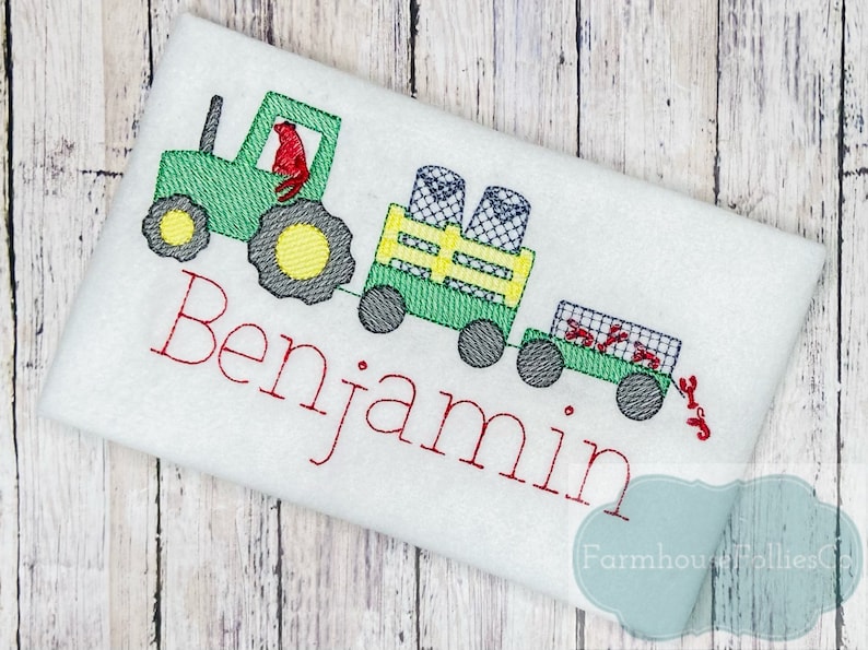 May include: Green tractor with a red figure in the driver's seat, pulling a wagon with a yellow crate and red crabs. The wagon is labeled "Benjamin".
