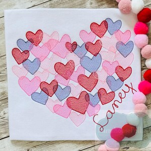 Pu&ograve; includere: Una maglietta bianca con un design a forma di cuore fatto di cuori rosa, rossi e viola. Il nome "Samey" &egrave; ricamato sotto il cuore.