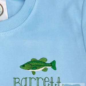May include: Light blue long-sleeved shirt with an embroidered green fish design and the name "Barrett" in green thread. The shirt is made of a soft, comfortable material.