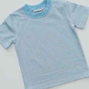 K&ouml;nnte beinhalten: Hellblau-wei&szlig; gestreiftes T-Shirt mit hellblauem Kragen und &Auml;rmeln. Das Shirt hat ein Etikett mit der Aufschrift "happy Mamba". Das Shirt ist aus einem weichen Material gefertigt.