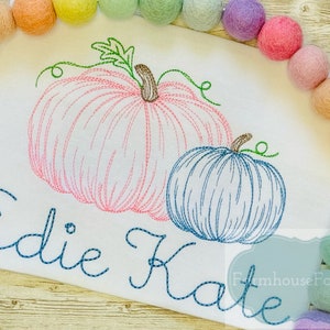 Puede incluir: Dise&ntilde;o bordado de dos calabazas, una rosa y una azul, con los nombres "Edie Kate" cosidos debajo.