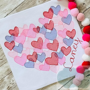 Pu&ograve; includere: Un tessuto bianco con un grande disegno a forma di cuore composto da cuori rosa, rossi e viola. Il nome "Laney" &egrave; ricamato in un font corsivo sotto il cuore.