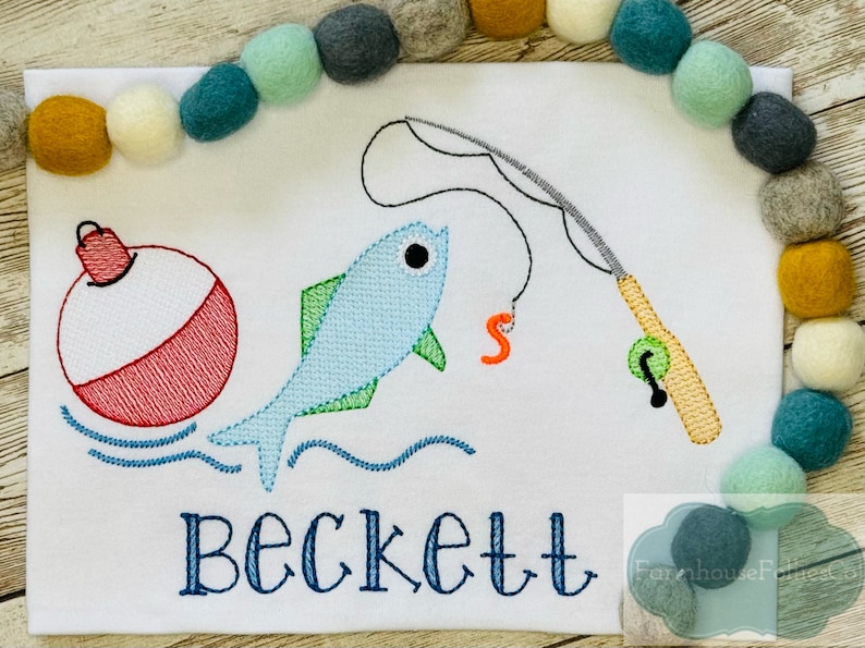 Puede incluir: Dise&ntilde;o bordado de un pez azul, un flotador rojo y blanco y una ca&ntilde;a de pescar con un flotador verde. El nombre Beckett est&aacute; bordado debajo del dise&ntilde;o.
