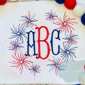 May include: White t-shirt with red, white and blue embroidered fireworks surrounding the letters "ABC".