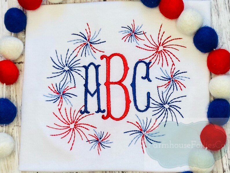 May include: White t-shirt with red, white and blue embroidered fireworks surrounding the letters "ABC".