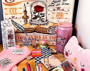 May include: A canvas tote bag featuring Belle's Book Club text, a rose in a glass dome, and a book. The collection includes a pink glitter tumbler, a cat-shaped pouch, pens, stickers, a bookmark, a scrunchie, and various stationery items.