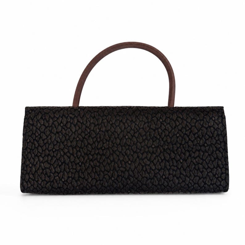 May include: A rectangular black handbag with a textured surface and a curved brown handle. The bag has a simple, elegant design, suitable for various occasions. The handle is made of a smooth, dark brown material.